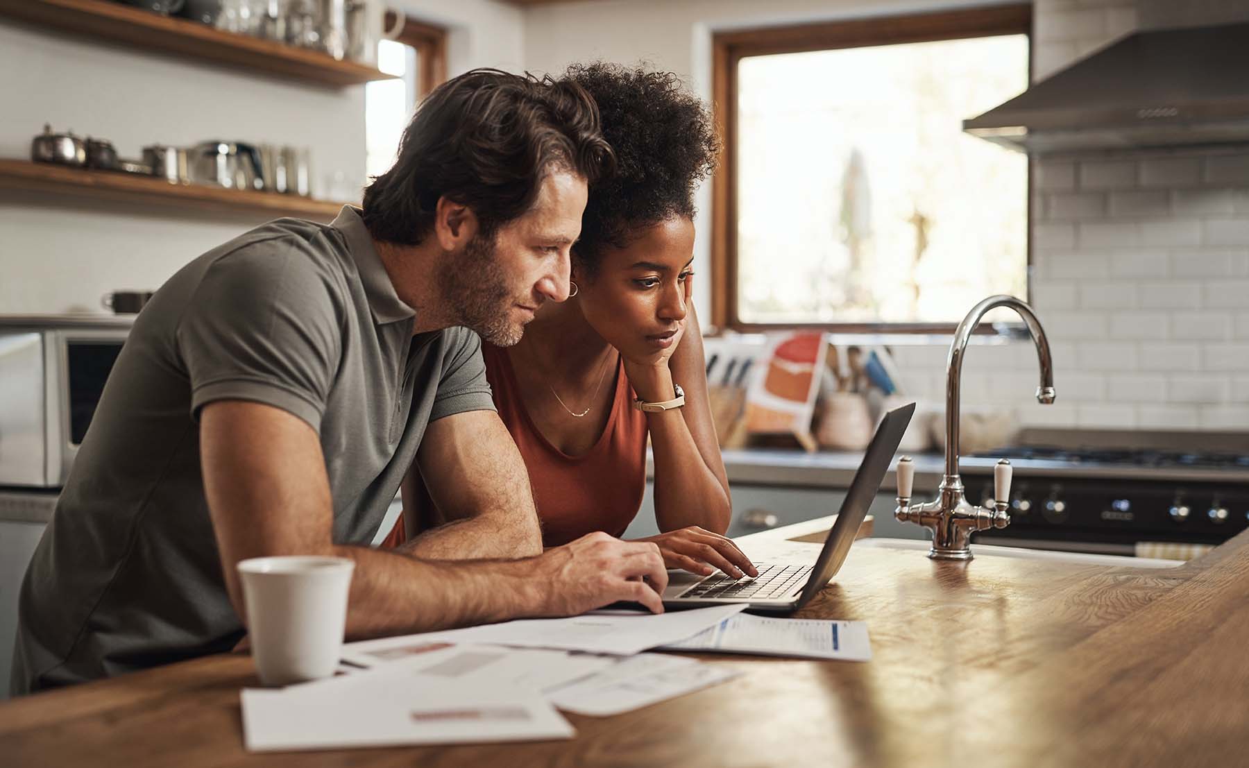 Couple looking at computer in home kitchen